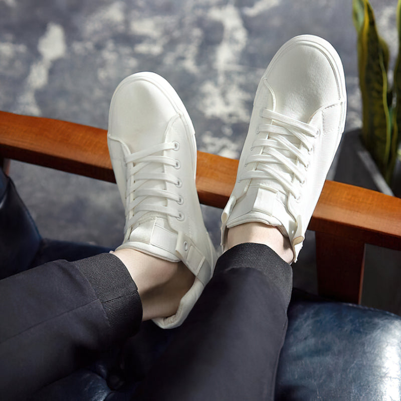 Breathable white canvas sneakers displayed on feet, resting on a stylish chair, blending comfort with casual street style.