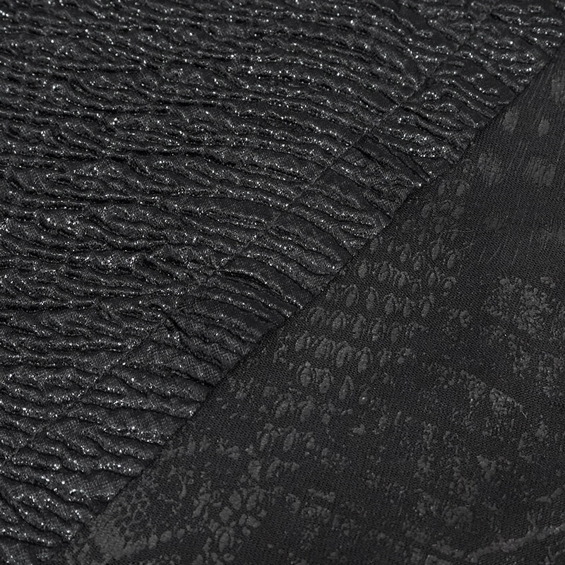 Close-up of textured black fabric with shiny and reptile-like patterns for punk clothing designs.
