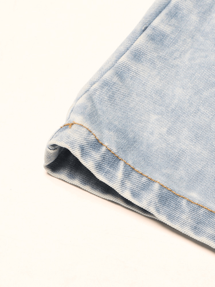 Close-up of the hem of fashionable high waist wide leg women’s spliced denim jeans in light blue.