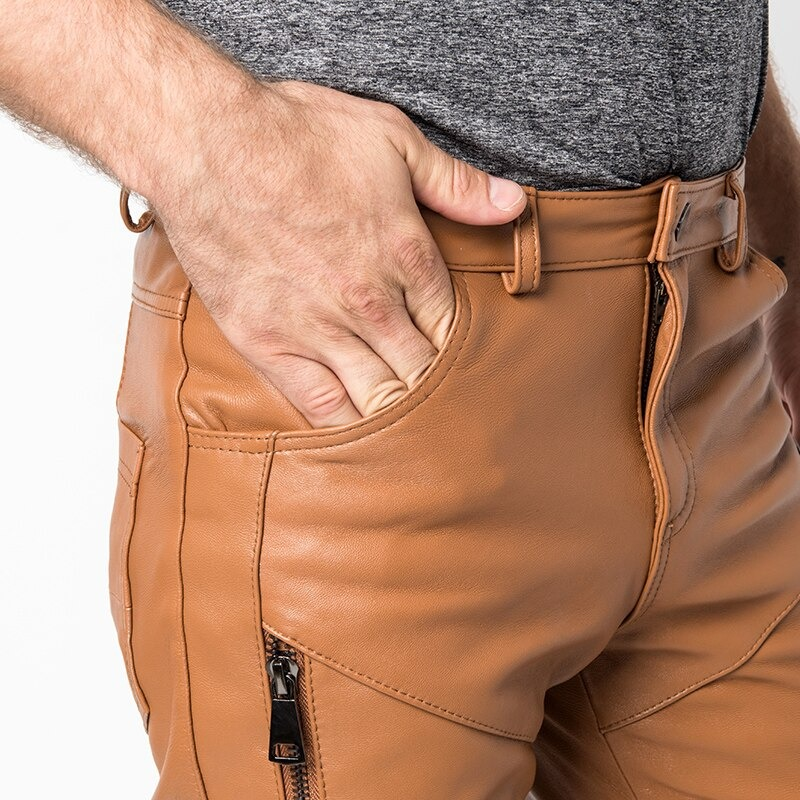 Close-up of a man wearing trendy leather skinny pants with zipper and hand in pocket, showcasing casual style.