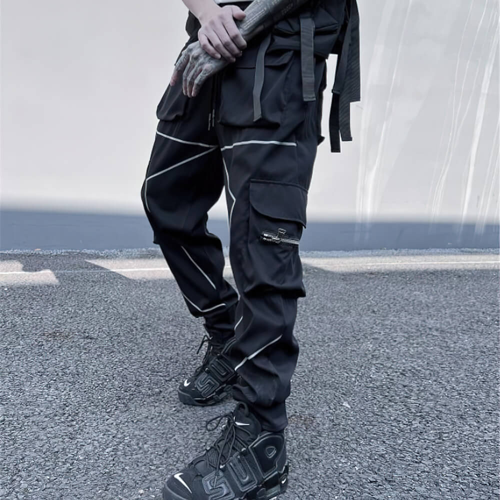 Men's black patchwork cargo trousers with pockets and elastic waist, paired with stylish sneakers.