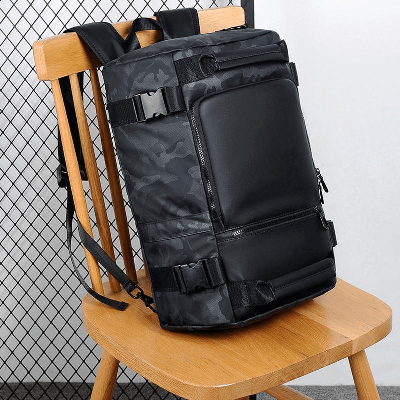 Fashion multifunctional waterproof backpack in stylish black camo design on a wooden chair.