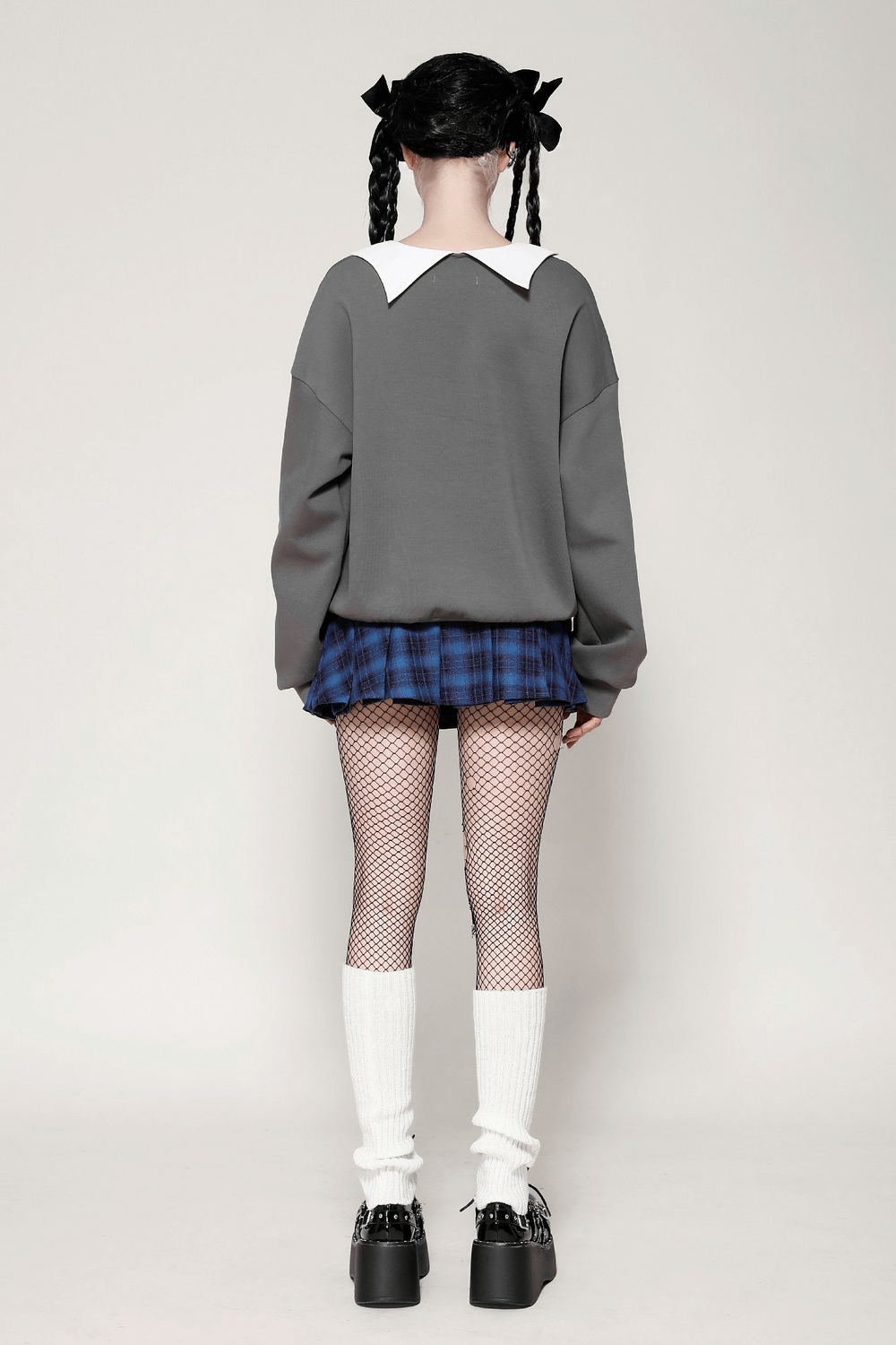 Fashionable model in a plaid mini skirt with star buttons, paired with a cozy sweater and knee-high socks.