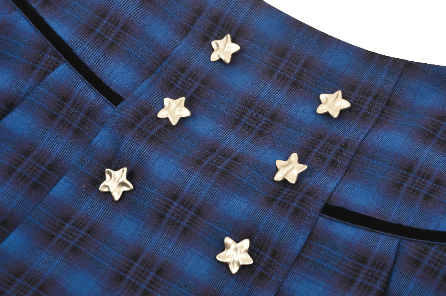 Close-up of star-studded buttons on a blue and black plaid mini skirt, showcasing Gothic style and edgy fashion.