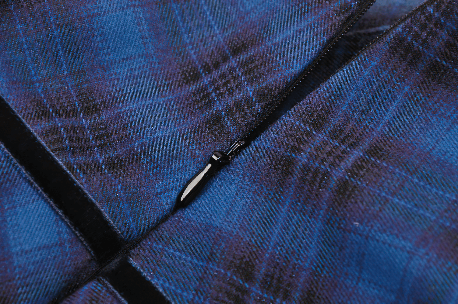 Close-up of blue and black plaid fabric highlighting the zipper detail of a stylish mini skirt. Perfect for a gothic flair!