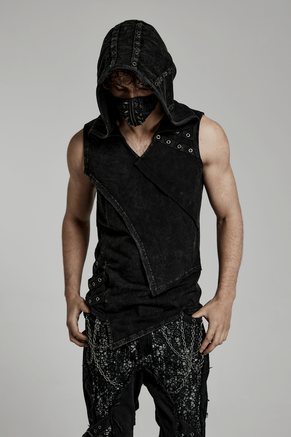 Man wearing a black distressed hooded vest with eyelets, showcasing a punk rock style.