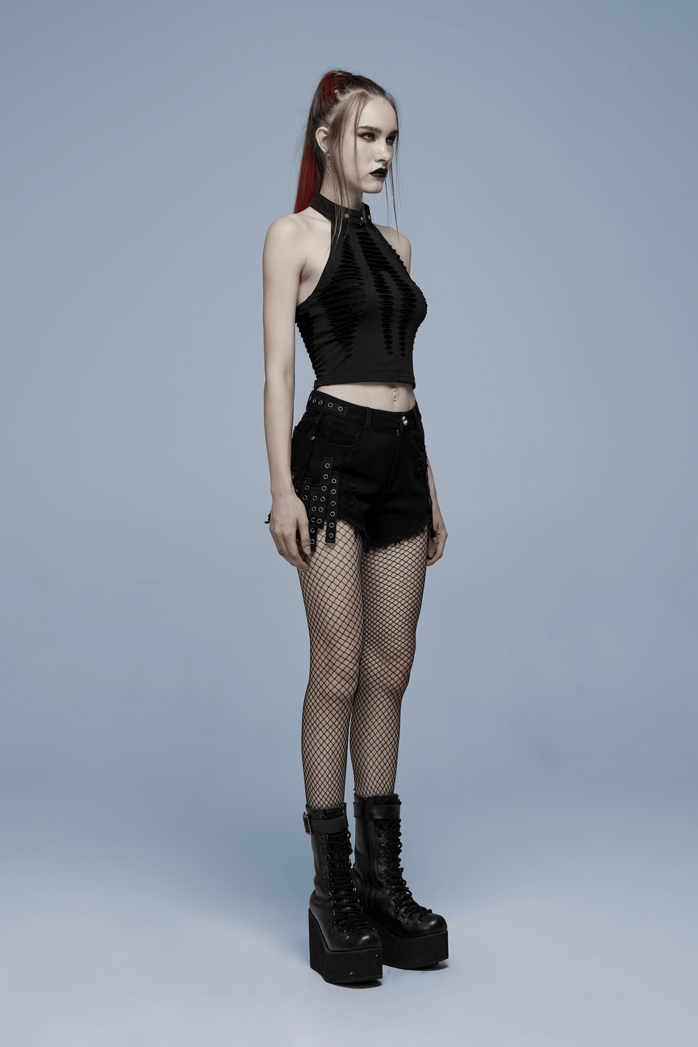 Model showcasing a stylish spider web mesh halter top paired with fishnet stockings and edgy black shorts.