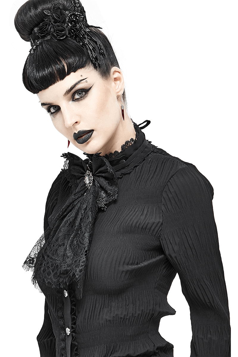 Gothic woman in a black shirt with a lace bow tie and silver brooch, showcasing vintage style accessories.