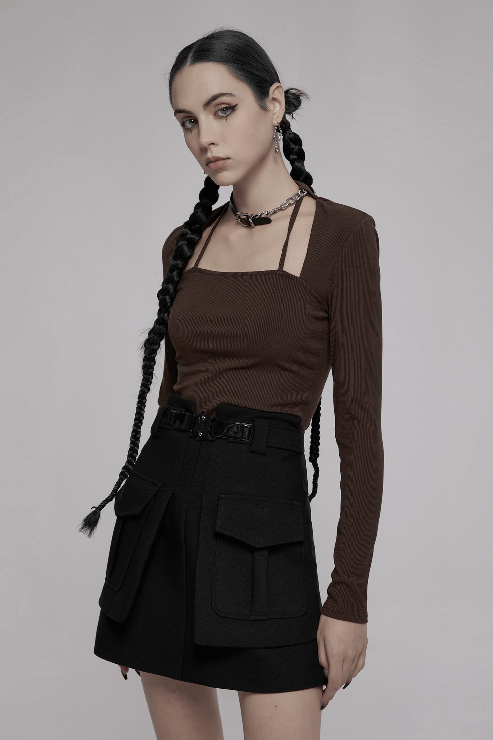 Trendy high-waist A-line skirt with unique buckle and stylish pockets, paired with a chic brown long-sleeve top.