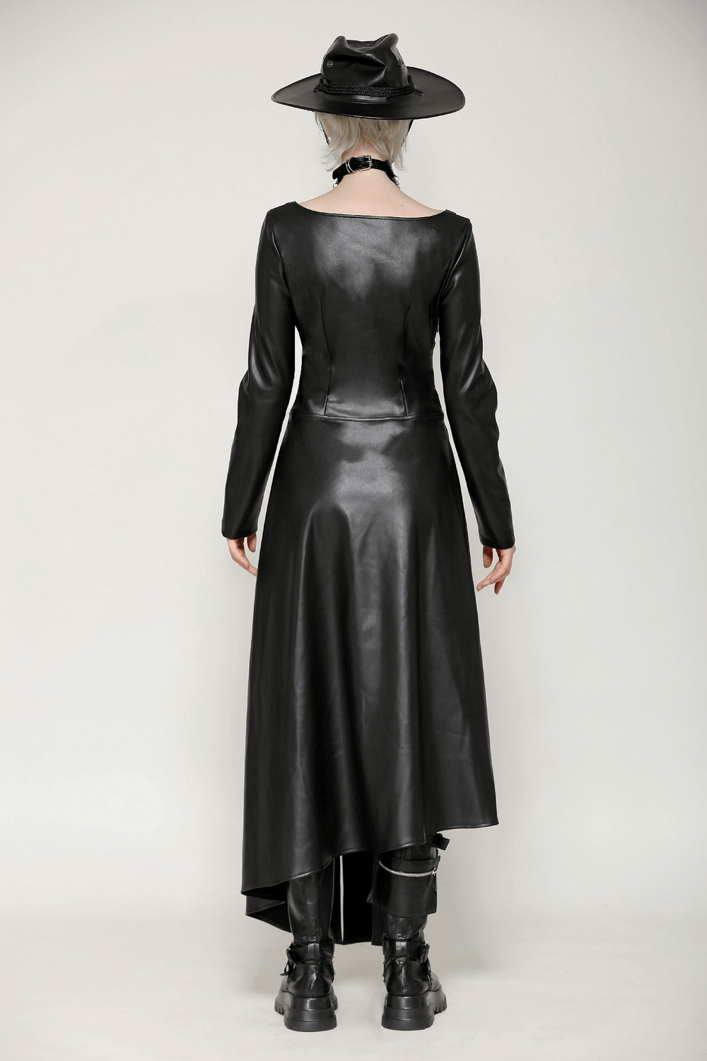 Back view of a stylish faux leather gothic dress with asymmetrical hem, complemented by a chic black hat and edgy boots.