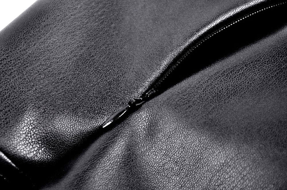 Close-up of a black faux leather fabric featuring a smooth zipper, highlighting the textured material and sleek design.