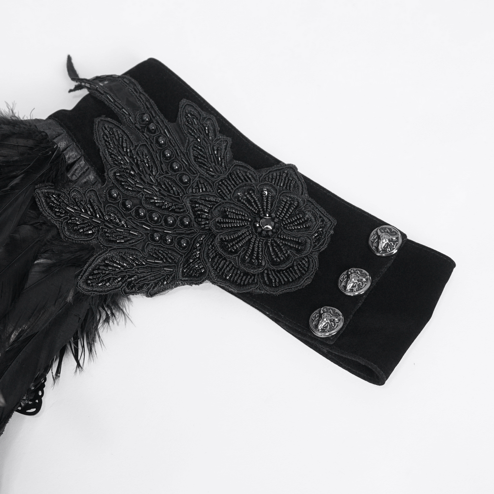 Close-up of a black feathered cape sleeve featuring intricate beadwork and embroidered floral design.