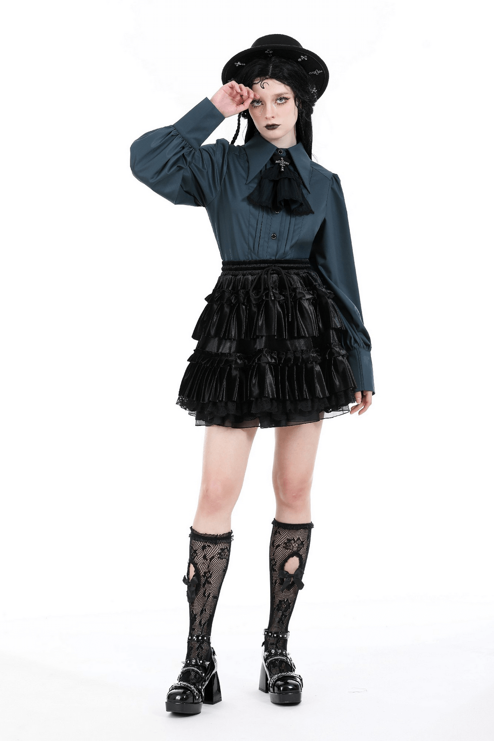 Stylish female model in a frilly layered black mini skirt with lace trim, paired with a blue blouse and trendy accessories.