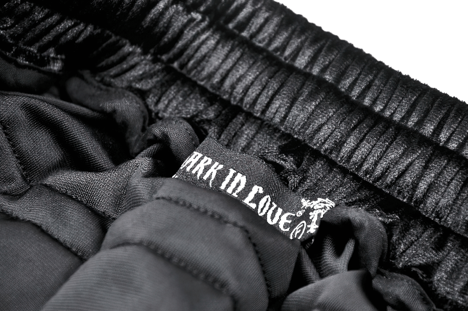 Inside label of a black velvet mini skirt, showcasing soft fabric and brand tag for elegance and comfort.
