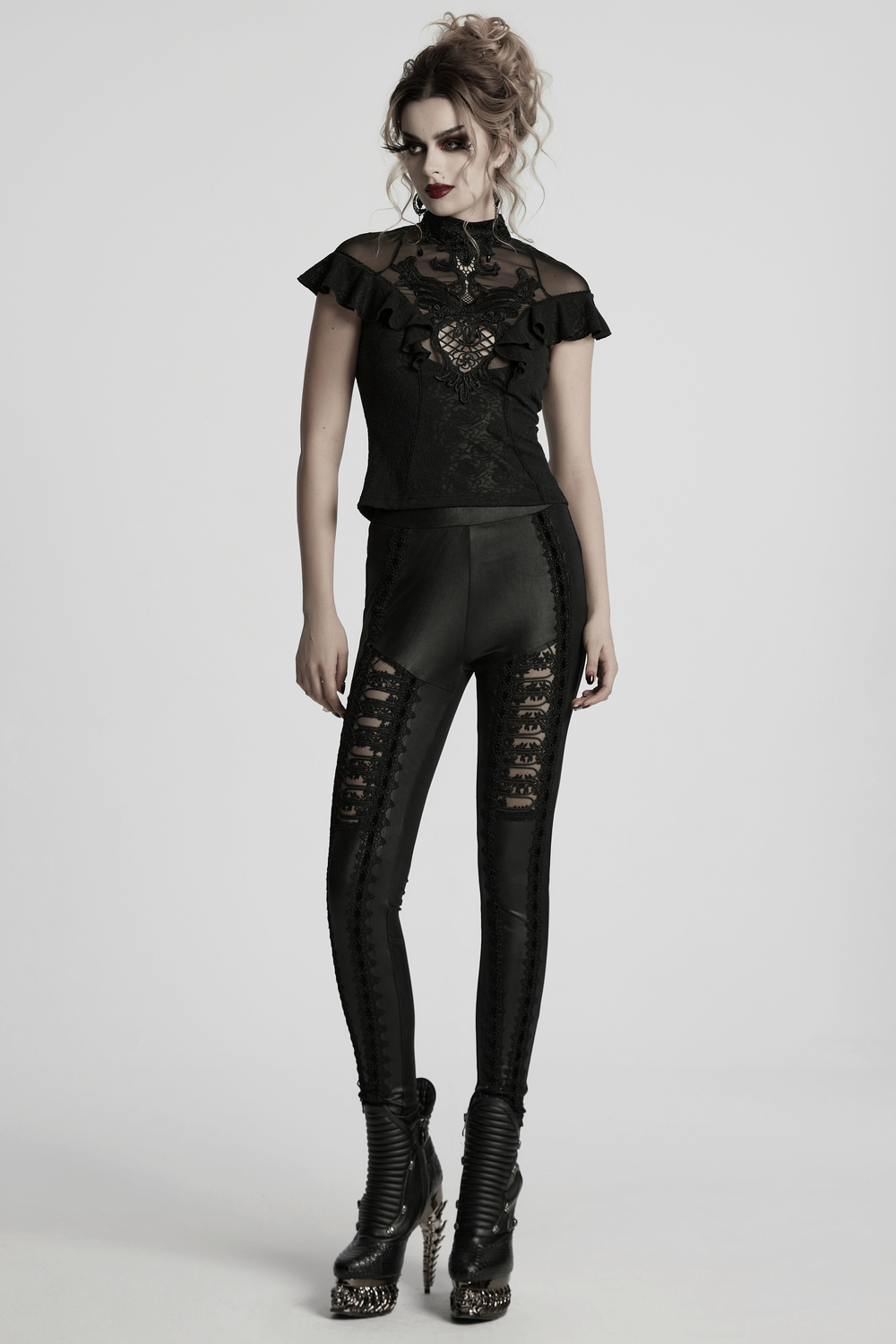 Gothic female model showcasing glossy black lace spliced leggings, styled with a trendy top and dramatic makeup.
