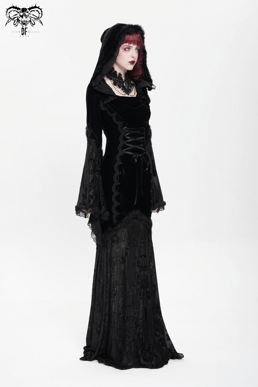 Gothic female model in black velvet hooded dress with lace trim and corset details, exuding dark elegance.