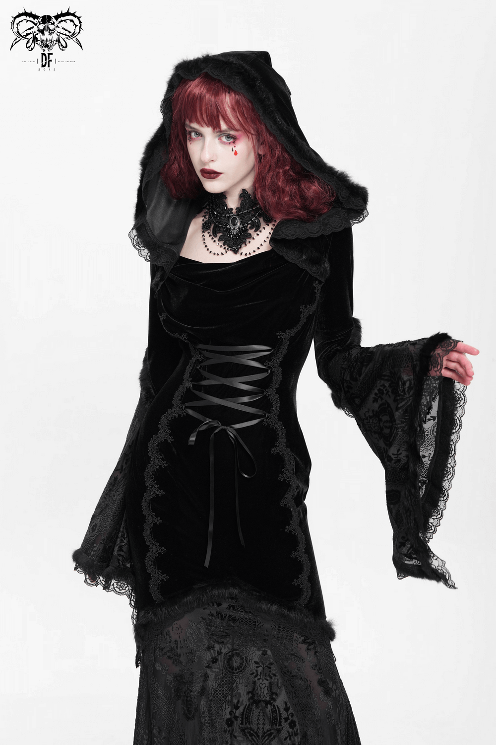 Gothic female model in a black velvet hooded dress with corset details and lace trim, exuding dark elegance.