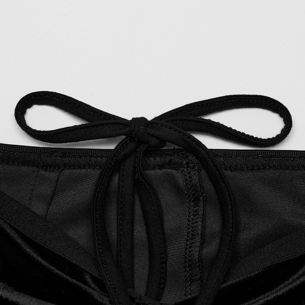 Close-up of a bow tie detail on black velvet flared pants' waist strap for women.