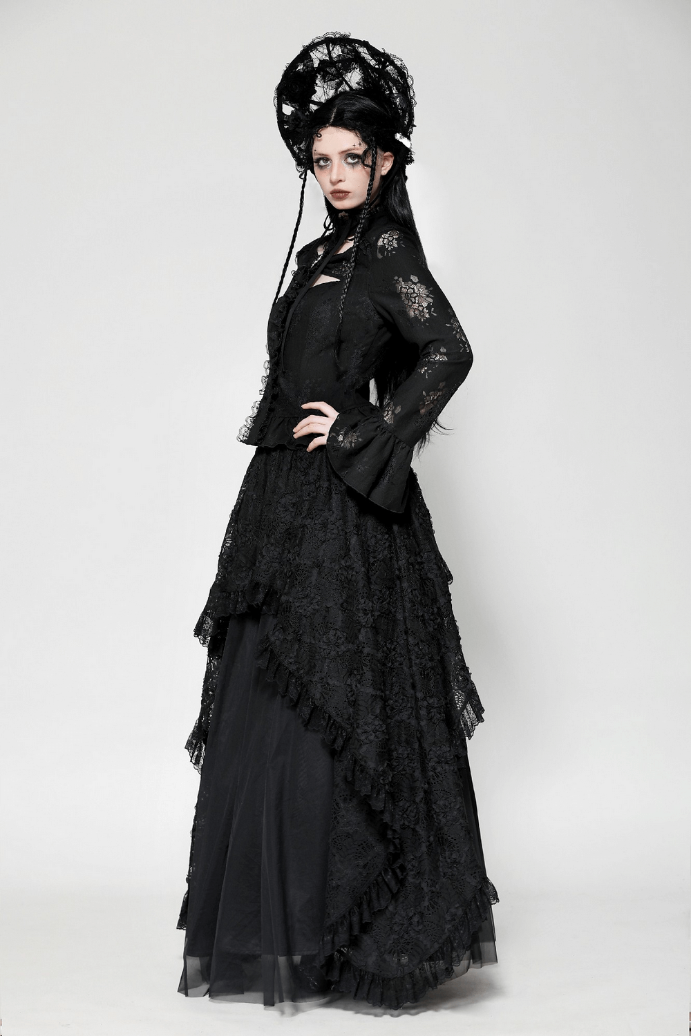 Elegant gothic model in a black lace blouse and layered skirt, showcasing bell sleeves and intricate lace details.