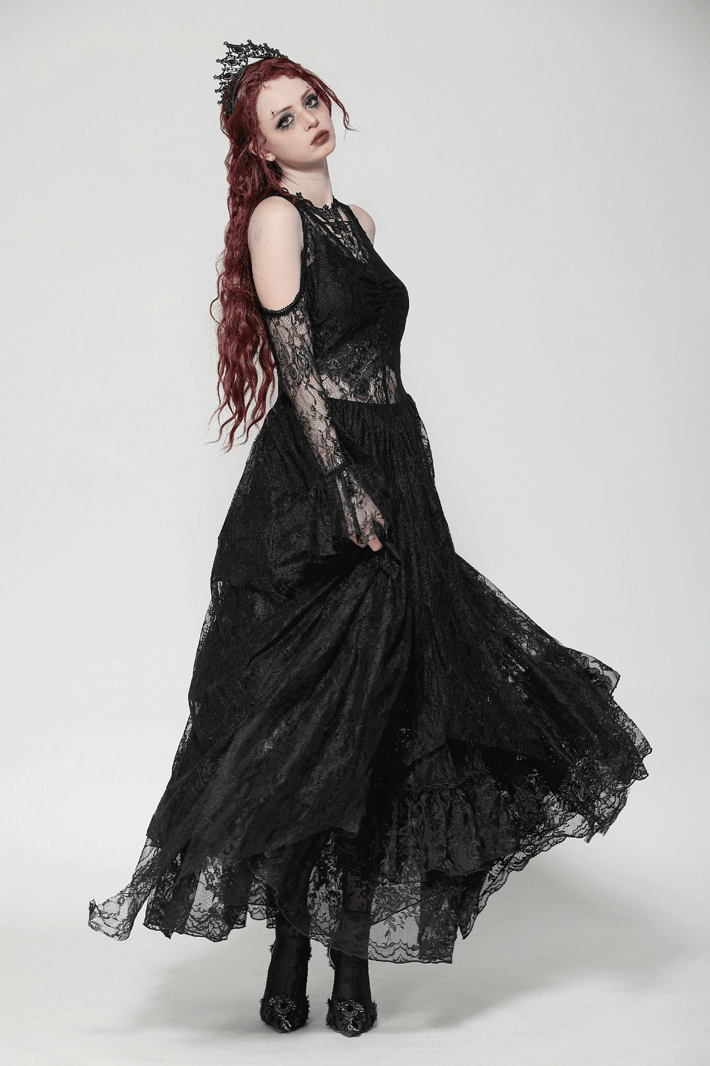 Elegant female model in a black gothic lace overlay maxi dress with sleeves, perfect for dramatic evening looks.