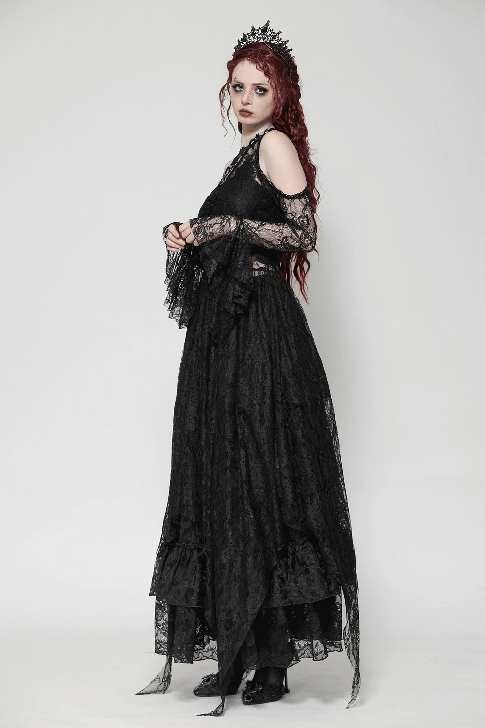 Elegant female in a black Gothic lace overlay maxi dress with sleeves and a dramatic crown accessory.