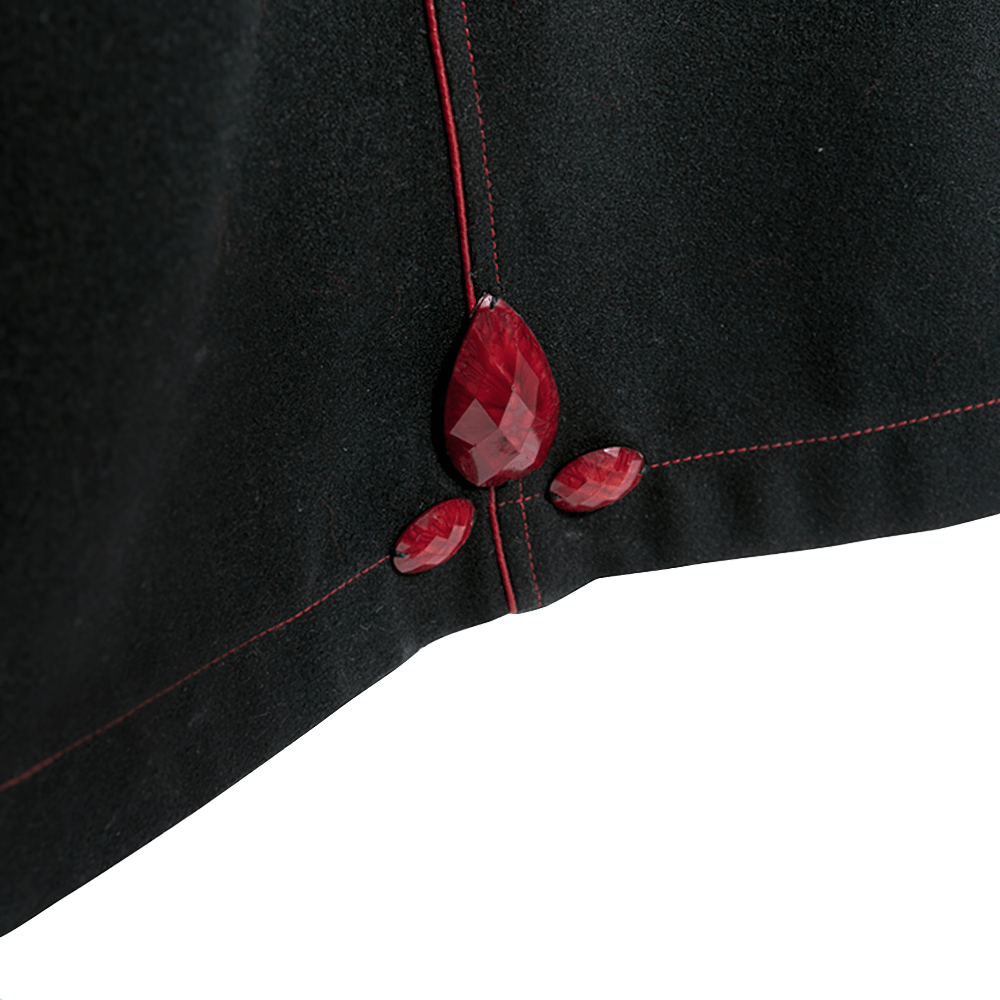 Close-up of elegant black fabric with striking red faux gems for a gothic long coat design.
