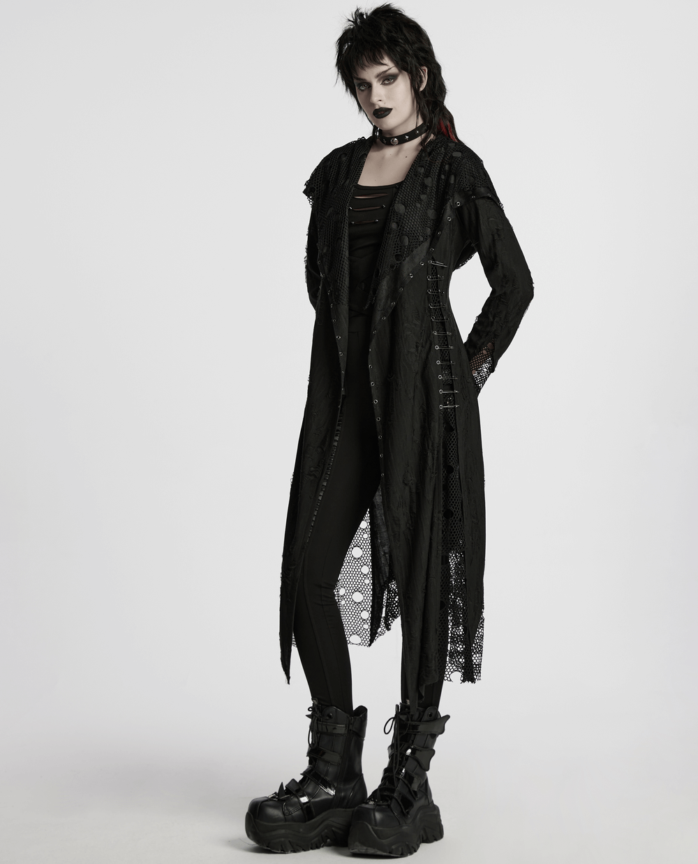 Female in Gothic mesh knit hooded coat with asymmetric hem, edgy style, paired with chunky boots.