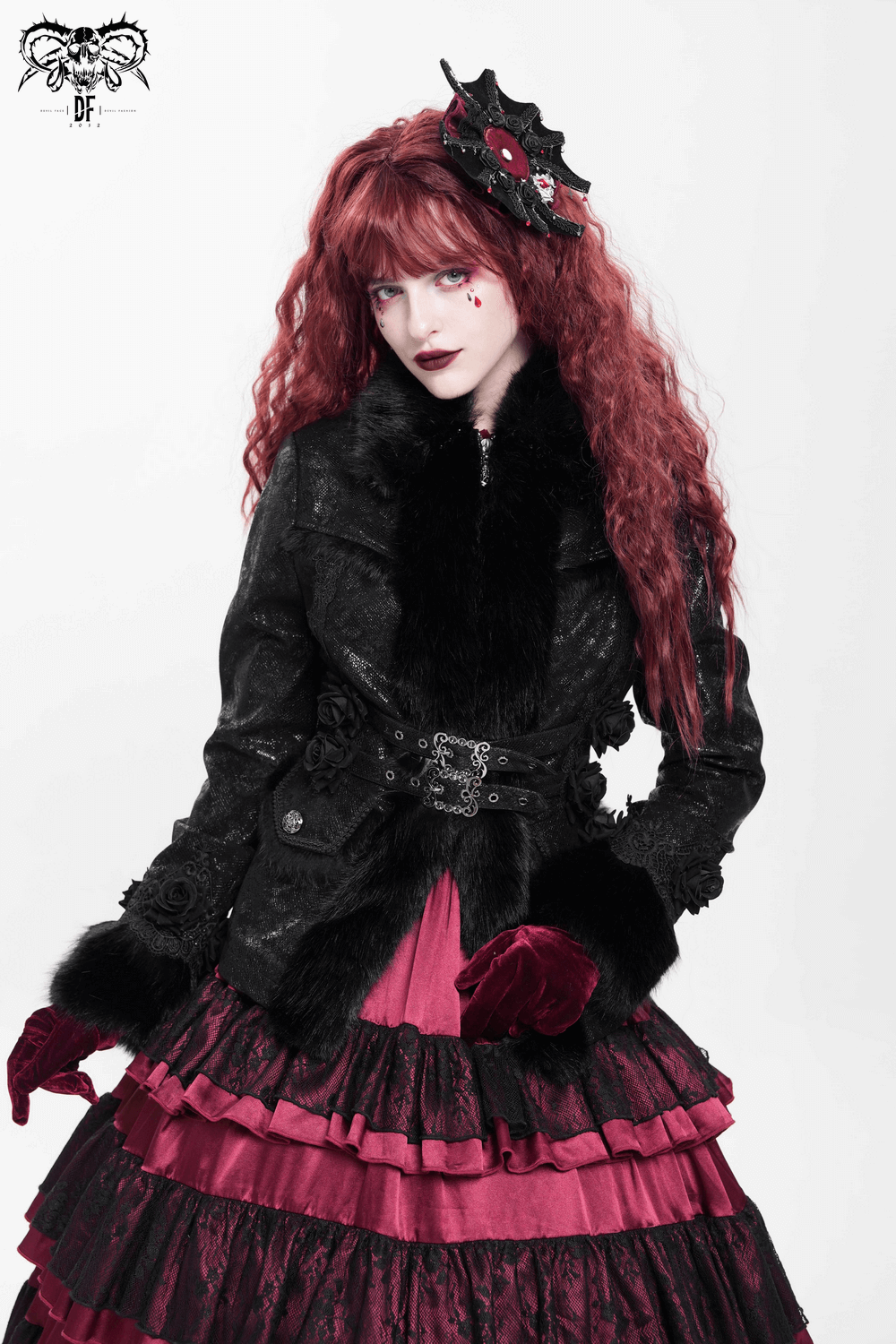 Gothic black jacket with faux fur trim, lace roses, and buckle details on a woman in dramatic pink dress.