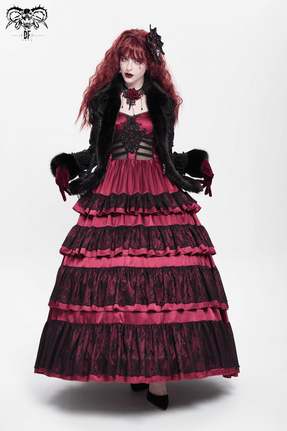 Gothic fashion model in layered black and burgundy dress with faux fur trim and lace accents, exuding alternative elegance.