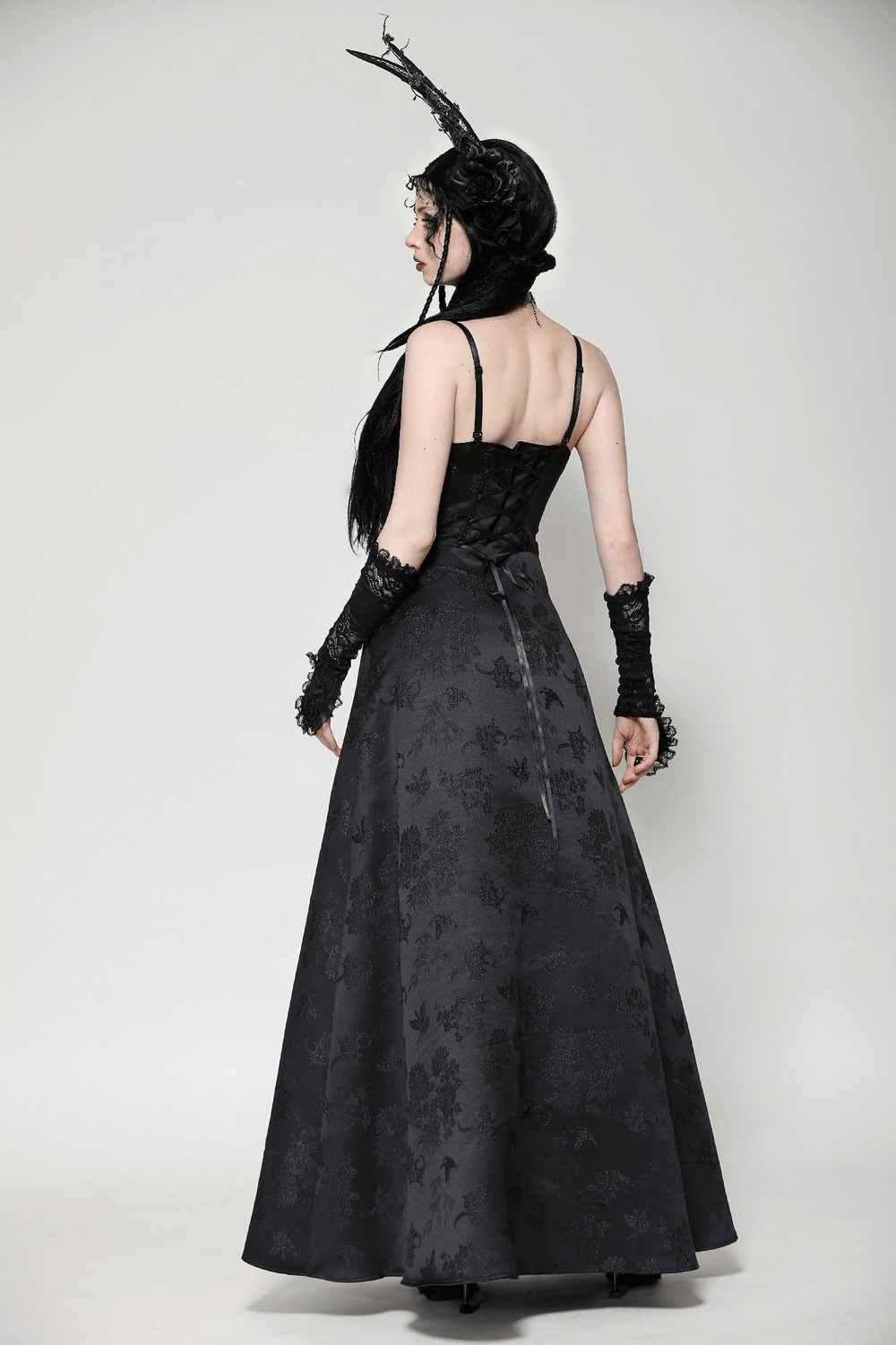 Elegant back view of a female in a black lace gothic maxi dress with floral embroidery and intricate lace details.