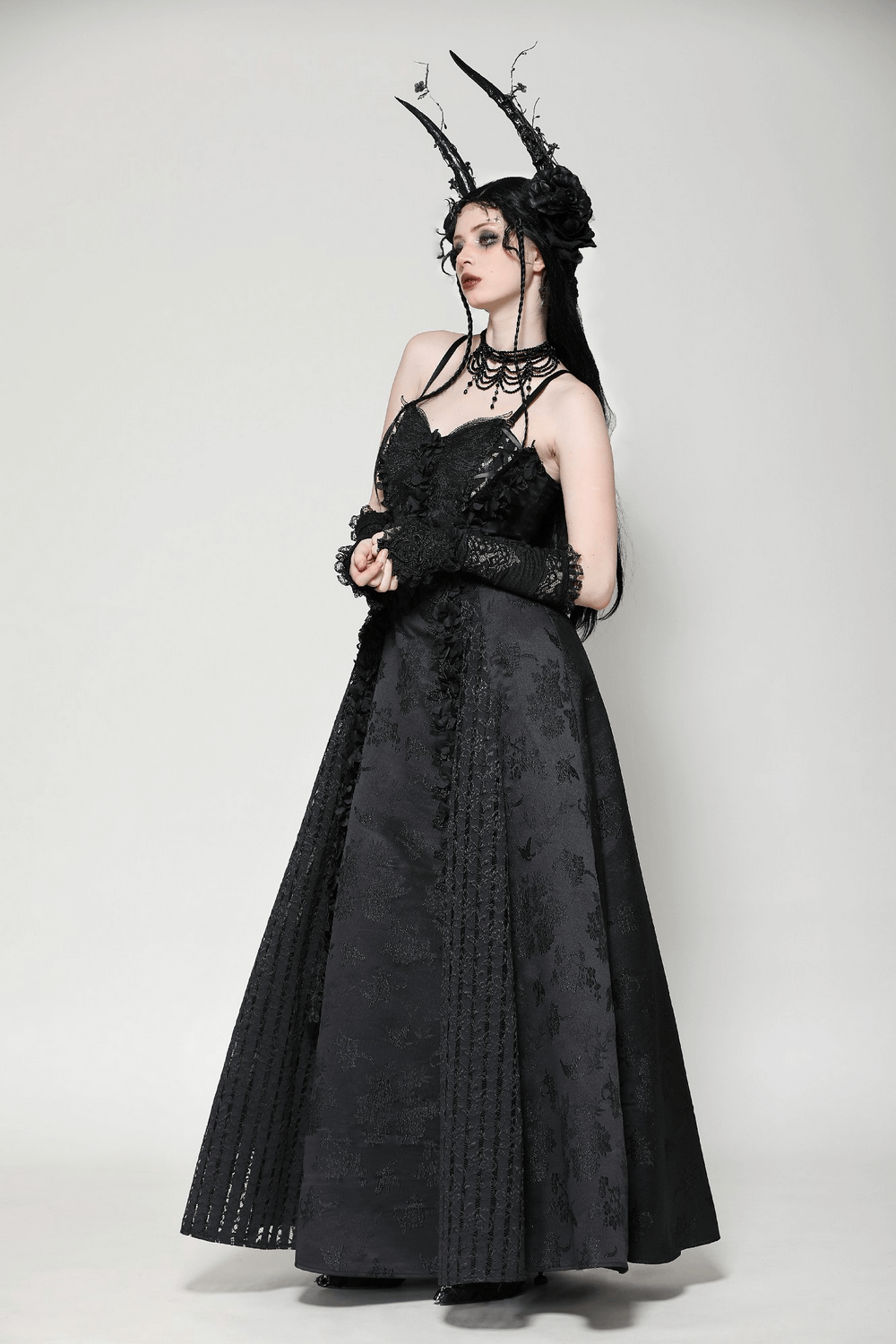 Elegant female model in a black lace gothic maxi dress with floral embroidery and dramatic styling.