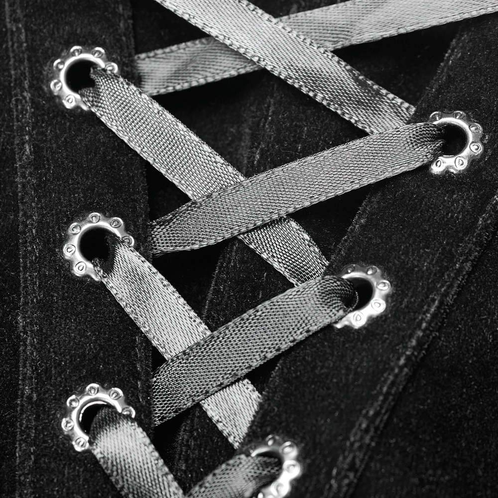 Close-up of black lace-up detailing with silver ribbon on gothic-inspired fabric.