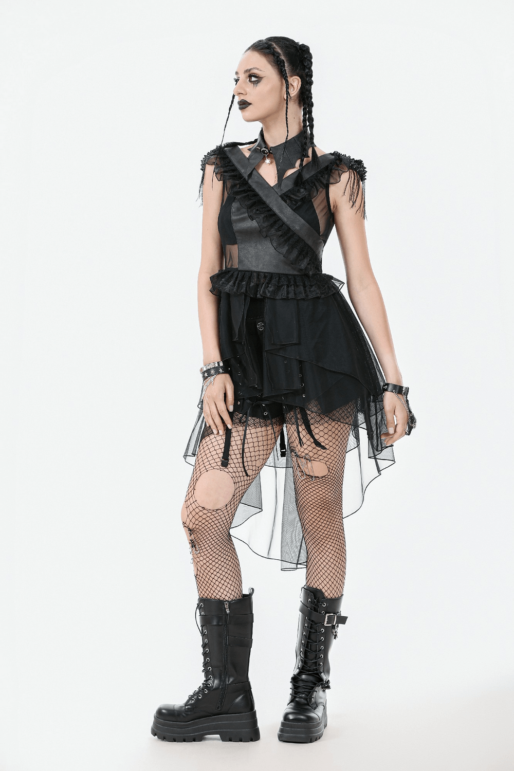 Gothic female model in lace-up tiered tulle dress with ruffles, fishnet stockings, and combat boots.