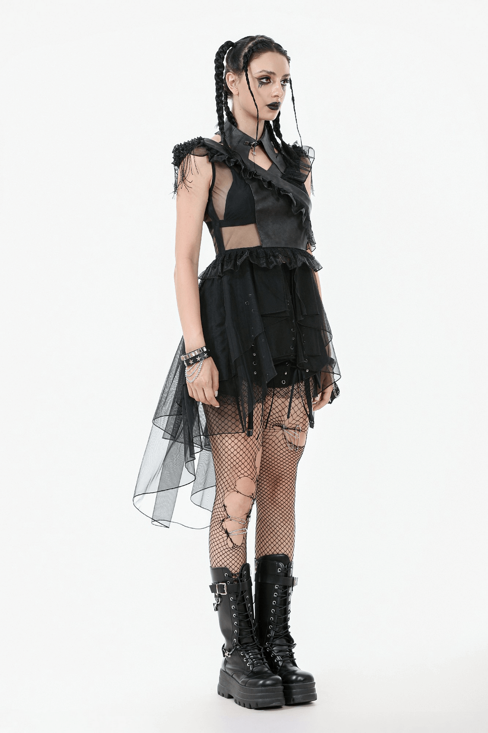 Gothic female model in a black lace-up tiered tulle dress with ruffles, paired with fishnet tights and chunky boots.