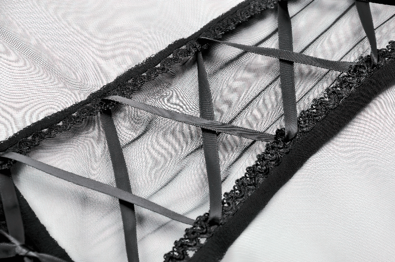 Close-up of a black lace-up detail on a gothic dress, featuring intricate ribbons and delicate lace trim.