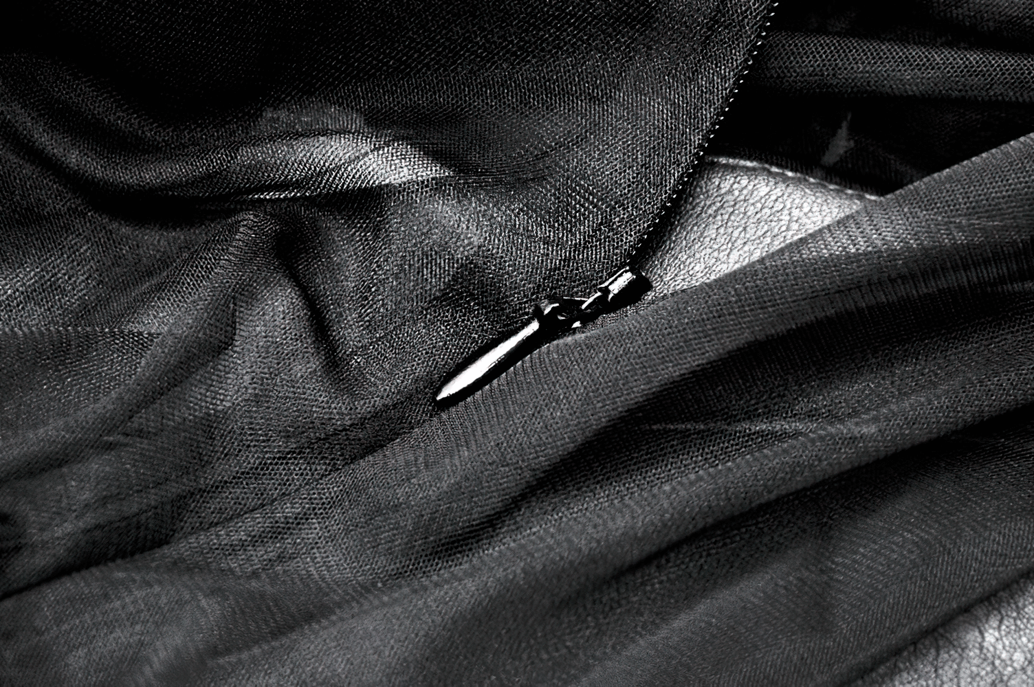 Close-up of a black lace fabric with a shiny zipper, showcasing the delicate texture and details.