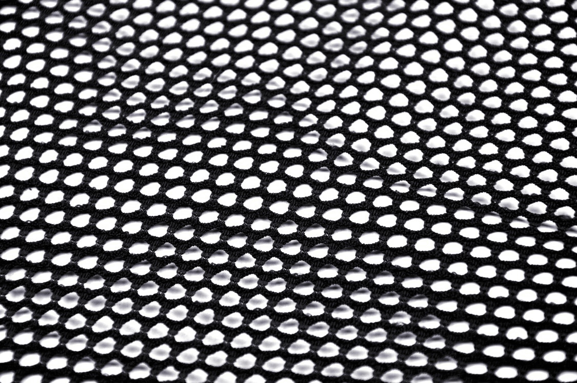 Close-up of sheer black mesh fabric featuring a perforated design, perfect for edgy punk fashion.