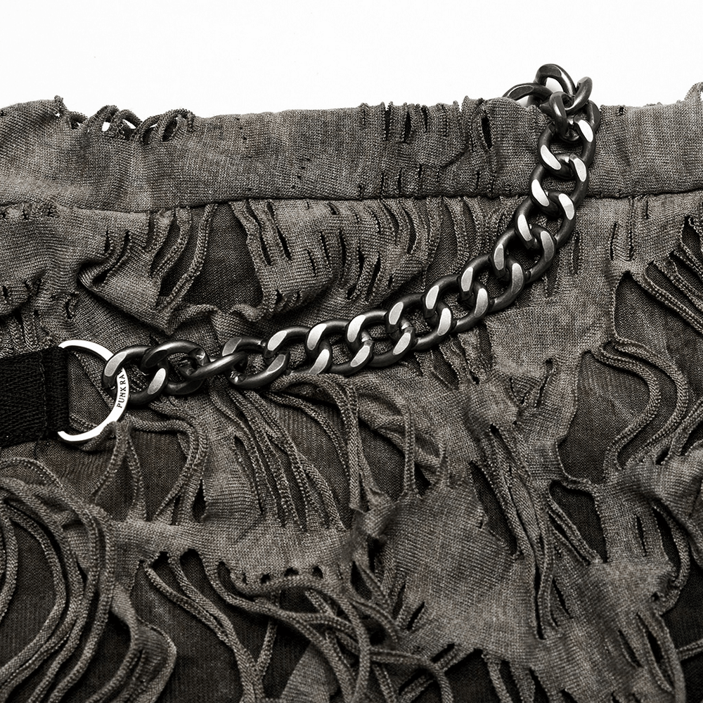 Close-up of ripped skinny trousers with punk-style chain detailing for a bold fashion statement.