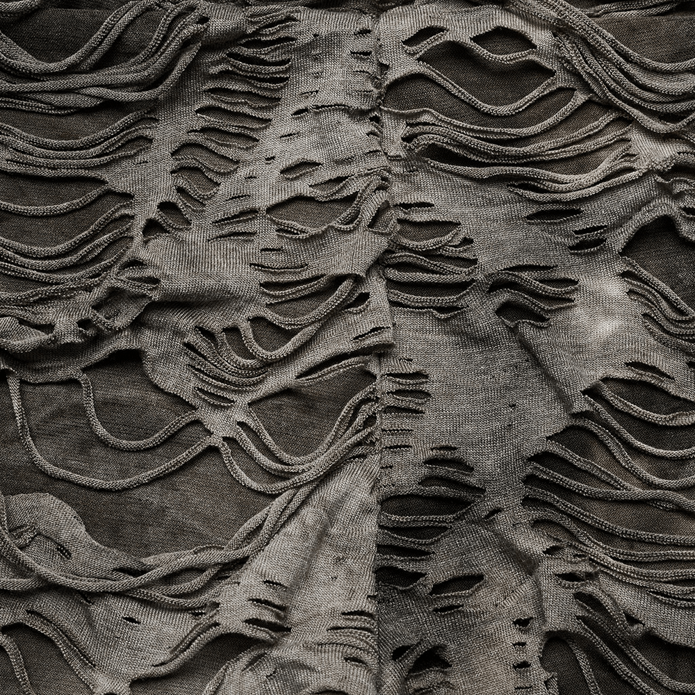 Close-up of ripped fabric with edgy fringe details, showcasing the punk rock style of female trousers.