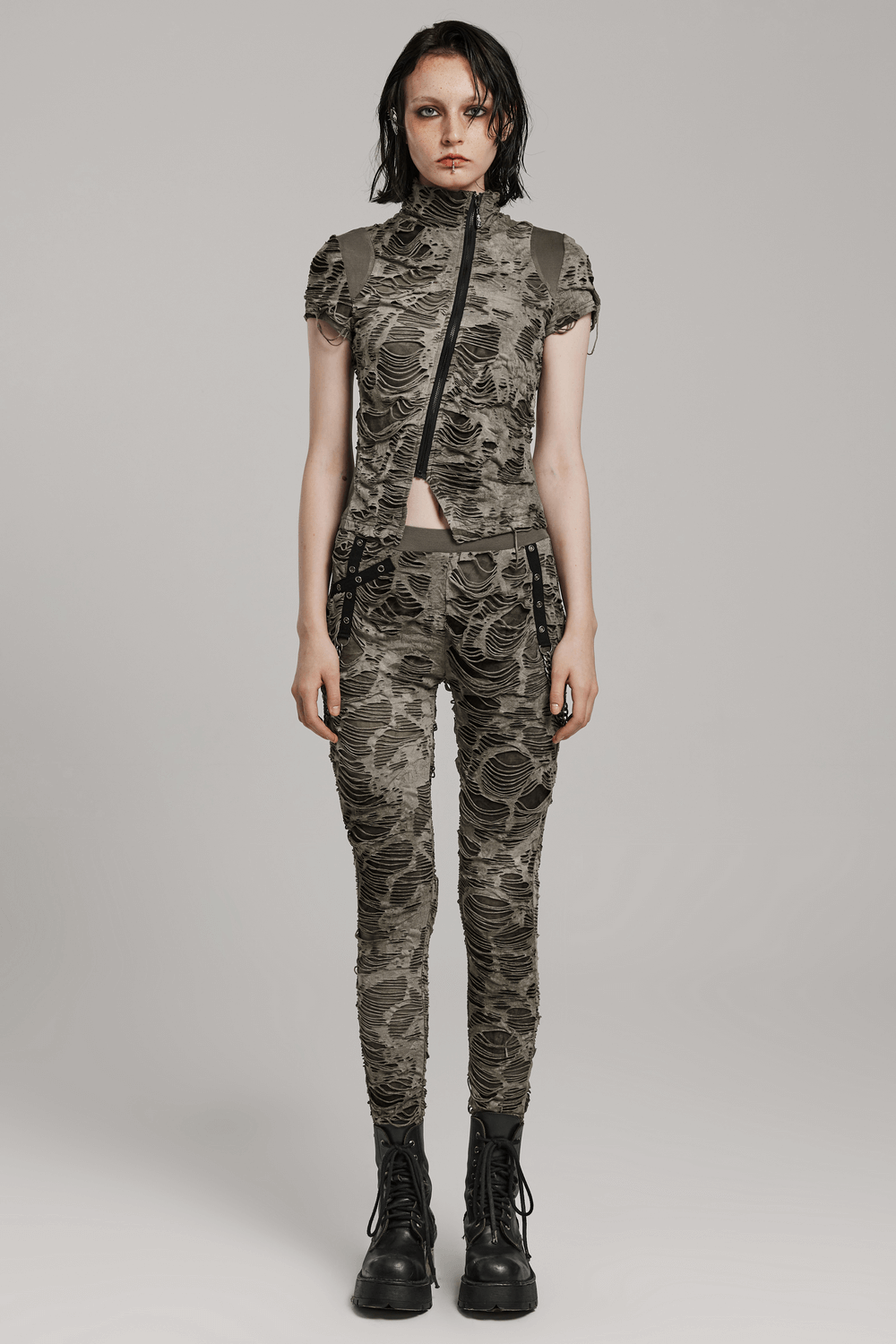 Female model in camo crop top and skinny trousers, showcasing edgy punk fashion style with combat boots.