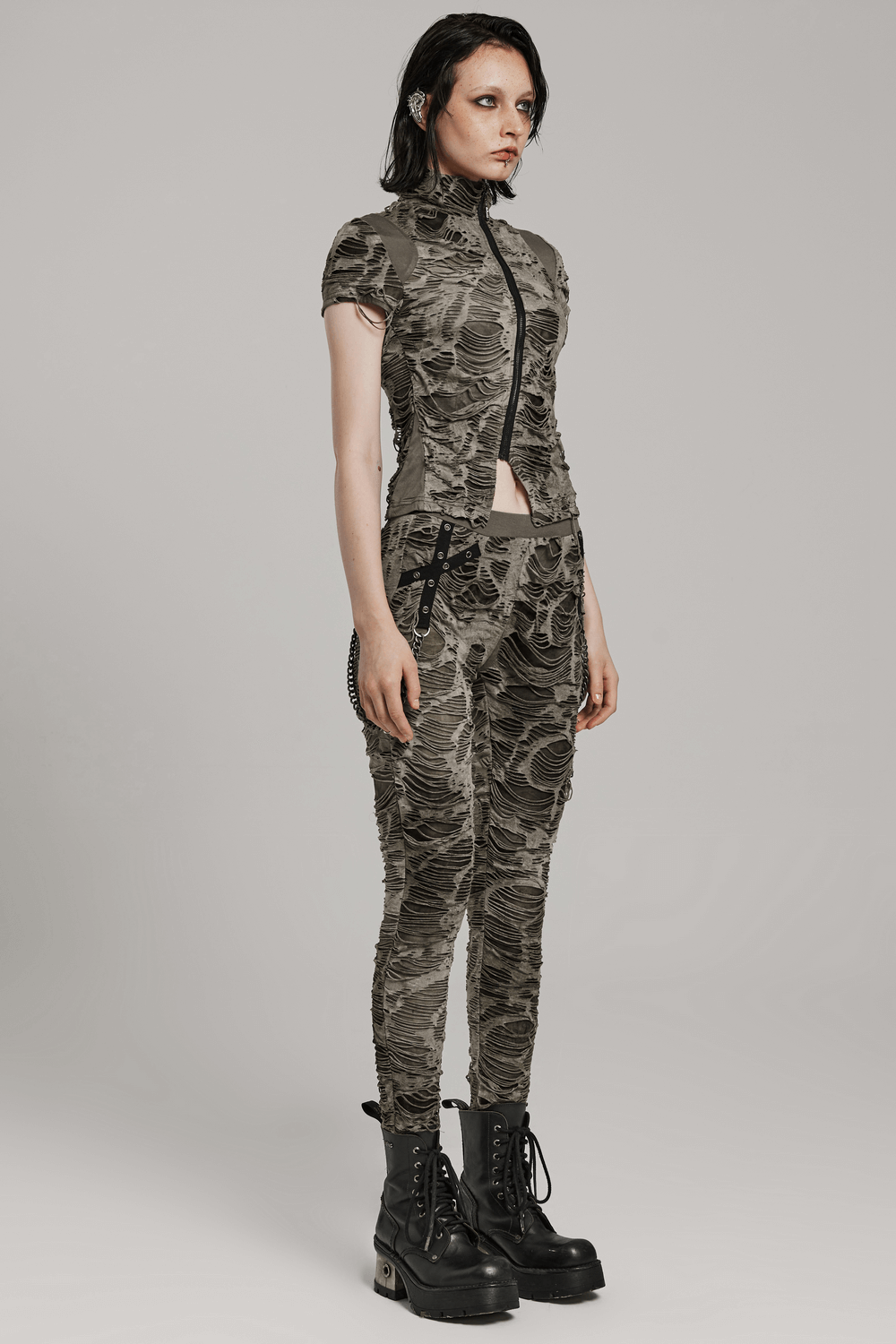 Edgy female model in fitted camo outfit with zip details and chunky boots, showcasing a punk rock style.