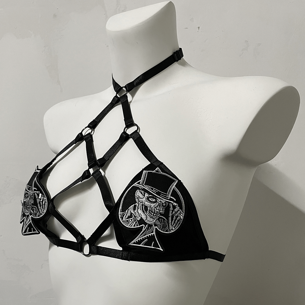 Gothic female strappy halter bra with playing card patches and adjustable harness design.