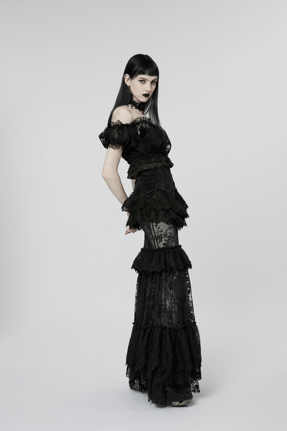 Chic model showcasing a gothic black dress with ruffles and lace, exuding elegance and allure.