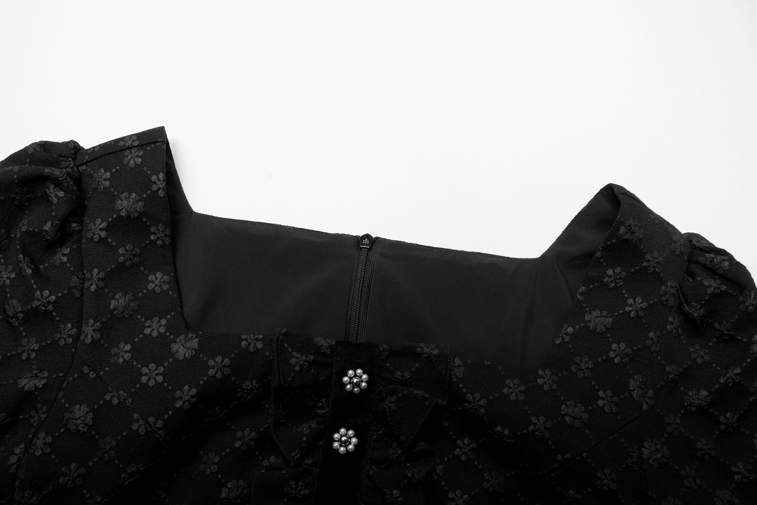 Close-up of the square neckline and pearl-detailed buttons of a floral jacquard dress.