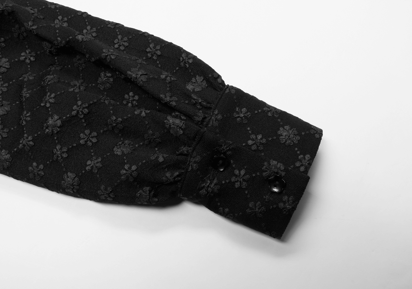 Close-up of a floral jacquard dress sleeve featuring a wide cuff and delicate black flower patterns.