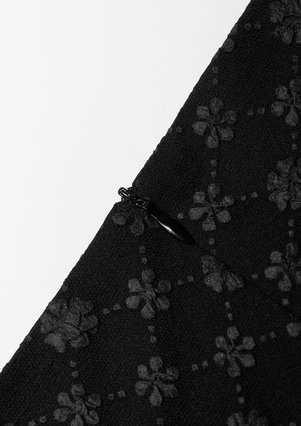 Detail of black floral jacquard fabric showcasing delicate flower patterns and elegant zipper.