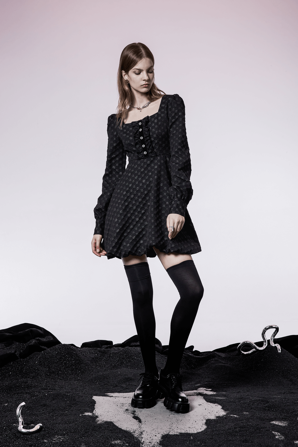 Model in a black floral Jacquard square-neck dress with puff sleeves and button detail, styled with knee-high socks.