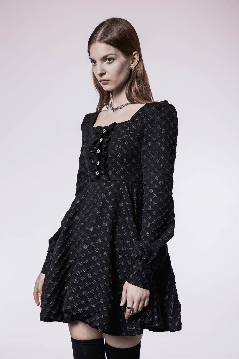 Model wearing a black floral jacquard square-neck dress with button detail and long sleeves.