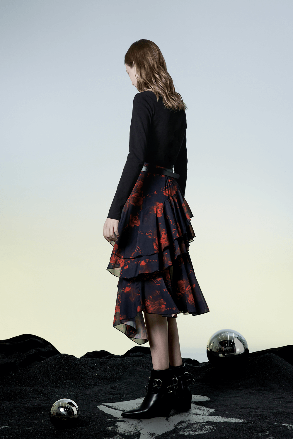 Model showcases flowy Punk Rave floral high-low skirt with layered hem against an artistic backdrop.