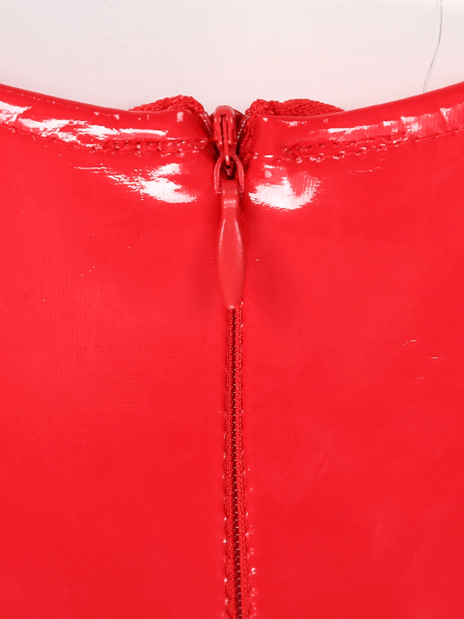 Close-up of a red patent leather jumpsuit zipper detail, showcasing the sleek and shiny texture.